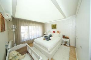een slaapkamer met een wit bed met een teddybeer erop bij Аристократичен апартамент в сърцето на Ямбол in Yambol