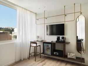 a room with a desk with a tv and a mirror at The Lekka Hotel & Spa in Athens