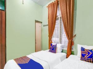 twee bedden in een kamer met een raam bij SPOT ON 91875 Nayla Homestay Syariah in Pekanbaru