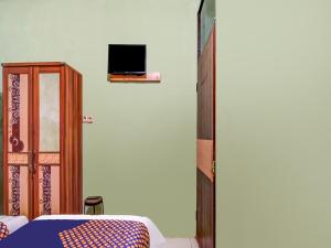 a bedroom with a bed and a tv on a wall at SPOT ON 91875 Nayla Homestay Syariah in Pekanbaru