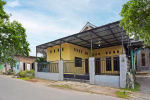 ein gelbes Gebäude mit einem Zaun vor einer Straße in der Unterkunft OYO Life 91869 Insan Mulia Kost Syariah in Mojokerto
