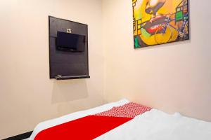 1 dormitorio con 1 cama y una pintura en la pared en OYO 91867 Gangnam Style Kutai en Surabaya