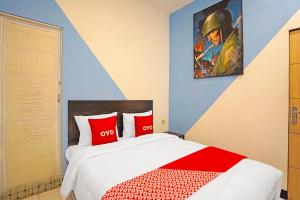 um quarto com uma cama com almofadas vermelhas e brancas em OYO 91867 Gangnam Style Kutai em Surabaya