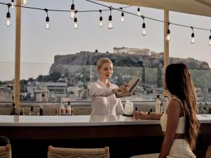 a woman standing at a bar holding a book at The Lekka Hotel & Spa in Athens
