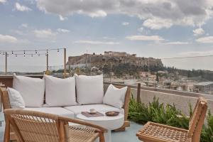 een balkon met een bank en uitzicht op de acropolis bij The Lekka Hotel & Spa in Athene