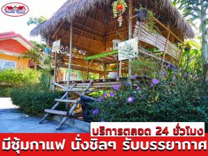 uma casa com uma cabana de palha com um banco e flores em อวบอิ๋มรีสอร์ท #ที่พักภูกระดึง em Ban Nong Tum