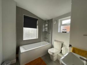 ein Badezimmer mit einer Badewanne, einem WC und einem Waschbecken in der Unterkunft Windmill View Apartments in Lincolnshire