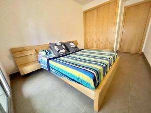 een slaapkamer met een bed met een gestreepte deken bij NEW! Apartamento con 2 piscinas, parque infantil, a 1 min de la playa in Sant Antoni de Calonge