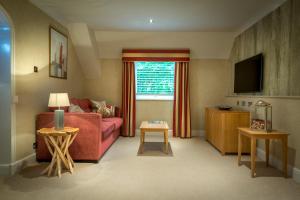 a living room with a red couch and a tv at Donnington Valley Hotel, Golf & Spa in Newbury