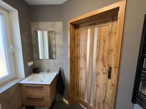 a bathroom with a sink and a wooden door at U Gruszków - domek pod Chojnikiem in Jelenia Góra