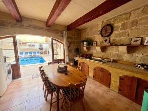 cocina con mesa de madera y piscina en Classic Farmhouse & Private Pool, en Mġarr