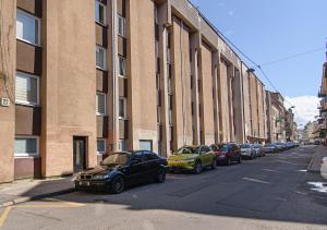 Una fila de autos estacionados en una calle al lado de un edificio en Hidden Submarine, en Vilna