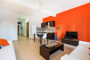 a living room with an orange accent wall at Lovely, Spacious High Floor APT in central PV & AC by 360 Estates in Paceville