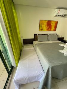two beds in a room with green curtains at Suíte na beira-mar do Resort Marulhos Muro Alto Porto Galinhas in Porto De Galinhas