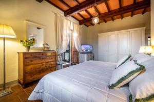 um quarto com uma grande cama branca e uma televisão em Villa S.Andrea em San Casciano in Val di Pesa