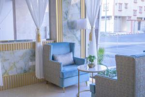 فندق واي هوتل في أبها: كرسي ازرق وطاولة في غرفة مع نافذة