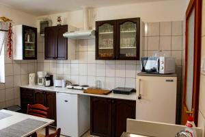 uma cozinha com armários castanhos e um frigorífico branco em Luca Apartman em Esztergom