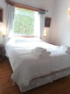 sypialnia z dużym białym łóżkiem i oknem w obiekcie Cabañas Trabunche w mieście San Martín de los Andes