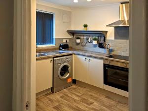uma cozinha com uma máquina de lavar roupa, um lavatório e uma máquina de lavar louça em Racecourse Apartment em Doncaster