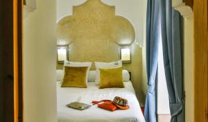 um quarto com uma grande cama branca com almofadas amarelas em Riad Alech em Essaouira