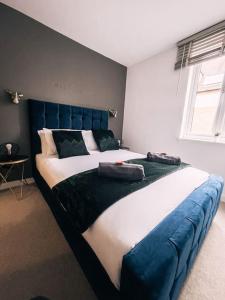a large bed with a blue headboard in a bedroom at Stunning Abbey Yard by Prescott Apartments in Abingdon