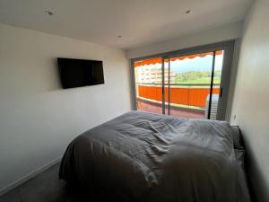 Schlafzimmer mit einem Bett und einem Flachbild-TV in der Unterkunft Appartement 2 pièces vue mer, à proximité de tout in Mandelieu-la-Napoule