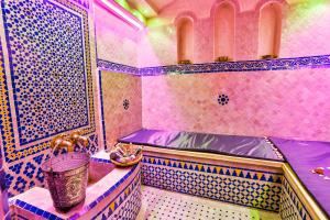 uma casa de banho com paredes em azulejo rosa e azul e um balde em Riad Alech em Essaouira