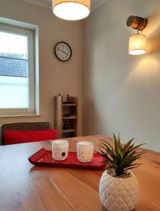 a table with two coffee cups and a plant on it at Ferienhaus Blaue Blume mit 11 kW Ladestation, Kamin, Terrasse, eingezäuntem Garten, Sauna, WLAN, Netflix, 2 Hunde willkommen! in Güntersberge