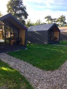 een tent met een tafel en stoelen in het gras bij Tenthuisje in het groen, een suite met eigen badkamer in Callantsoog