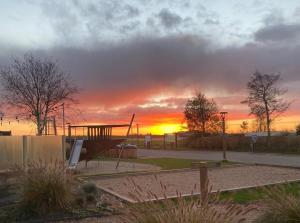 a sunset over a park with a bench in a park at Tenthuisje in het groen, een suite met eigen badkamer in Callantsoog