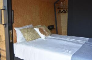 a bed with white sheets and pillows on it at Tenthuisje in het groen, een suite met eigen badkamer in Callantsoog