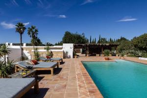 a swimming pool with chaise lounge chairs next to a house at Elegant Restored Luxury 600 Year Old Farmhouse I Las Chumberas I 6 Bedrooms I Stunning Views I Santa Gertrudis in Santa Gertrudis de Fruitera