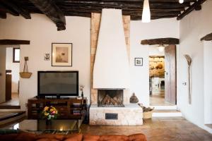 ein Wohnzimmer mit einem TV und einem Kamin in der Unterkunft Elegant Restored Luxury 600 year old Farmhouse Las Chumberas 6 Bedrooms Stunning Views Santa Gertrudis in Santa Gertrudis