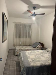 - une chambre avec 2 lits et un ventilateur de plafond dans l'établissement Apto 16 - Aconchegante - Praia das Astúrias - Guarujá - SP, à Guarujá