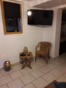 sala de estar con TV, silla y mesa en Gîte "Au dépôt" en Mesnières-en-Bray