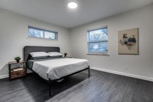 a white bedroom with a bed and two windows at Sweet Retreat in North Dallas in Dallas