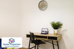 a desk with a chair and a clock on a wall at Syster Properties Leicester large home for Contractors, Families , Groups in Leicester