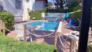 un patio trasero con piscina, sillas y mesa en Villa Elisabeth, en Lignano Sabbiadoro
