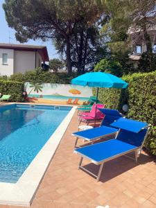 un grupo de sillas y sombrillas junto a una piscina en Villa Elisabeth, en Lignano Sabbiadoro