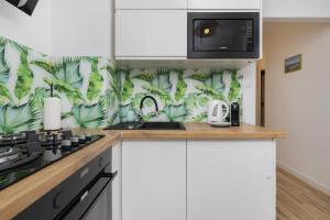 a kitchen with white cabinets and a green leafy wallpaper at Dedala Apartment 300m to the Beach by Renters in Gdynia