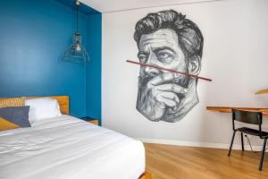 dessin d'un homme sur un mur à côté d'un lit dans l'établissement Selina Porto, à Porto