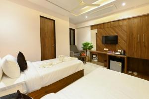 um quarto de hotel com duas camas e uma televisão em Hotel Avalon Palms Agra em Agra