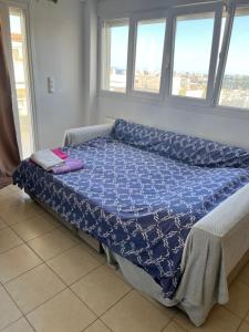 een bed met een blauw dekbed in een kamer met ramen bij Christos in Rafina