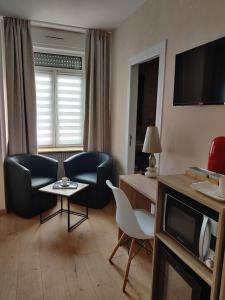 聖路易的住宿－cocon des lys，客厅配有两把椅子、一张桌子和一台电视