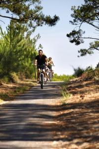 dos personas montando bicicletas por un camino en Les Coquillages, en Mimizan-Plage