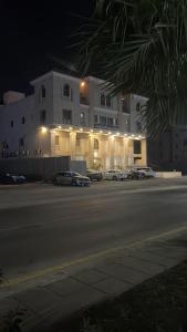 a building with cars parked in a parking lot at night at Rose Neri Lavender روز نيري الخزامى in Al Khobar