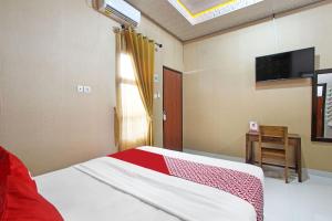 a bedroom with a bed and a flat screen tv at OYO 91842 Tahesa Guesthouse Syariah in Cilacap