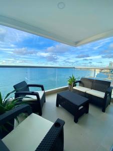 a balcony with chairs and tables and a view of the water at Cartagena Palmetto Beach Bella Vista in Cartagena de Indias