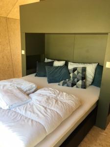1 dormitorio con 1 cama grande y cabecero grande en Tiny House in het groen, aan zee met privé Hottub en Callantsoog