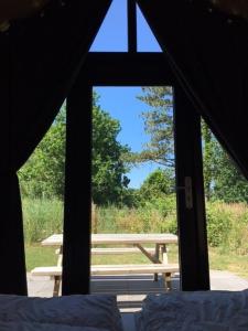una finestra con vista su una tenda e tavolo da picnic. di Tiny House in het groen, aan zee met privé Hottub a Callantsoog